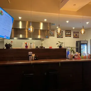 a restaurant counter with a tv on the wall