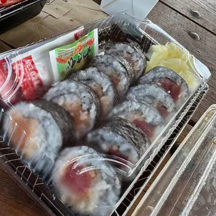 donuts in a plastic container on a picnic table