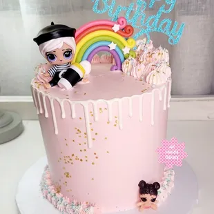 a pink birthday cake with a doll on top