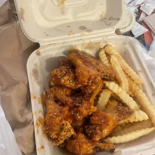 chicken wings and french fries in a styrofoam container