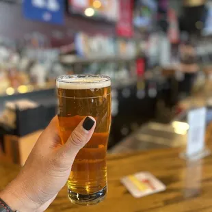 a hand holding a pint of beer