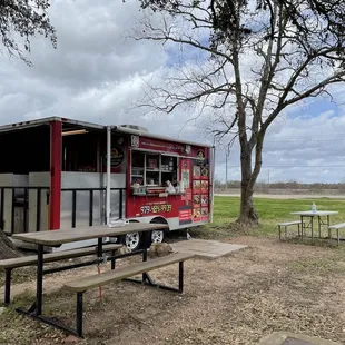 A cute small food truck with two dining tables