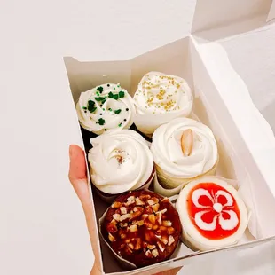 a hand holding a box of cupcakes