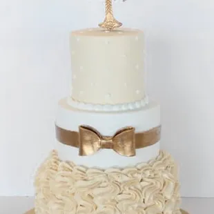 a three tiered cake with a gold cross on top