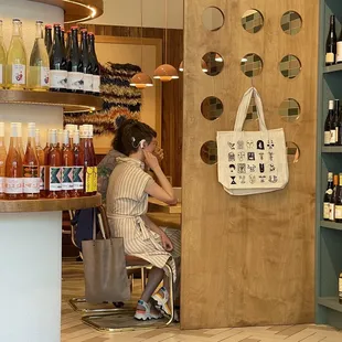 a woman sitting at a counter in a wine shop