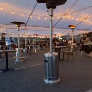 a patio with tables, chairs, and a gas heater