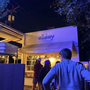 a group of people standing outside of a restaurant