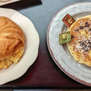Breakfast sandwich on croissant and chocolate chip / banana pancakes.