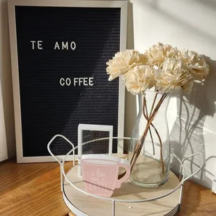 a vase of flowers and a sign on a shelf