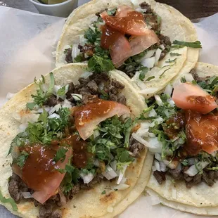 Steak tacos with onion, cilantro and tomatoes.