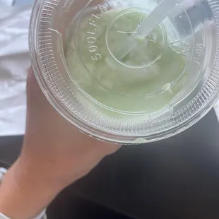 a hand holding a plastic cup with a drink in it