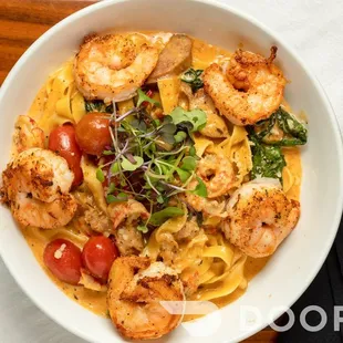 a bowl of pasta with shrimp and tomatoes