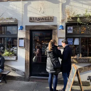 two people standing outside of a restaurant