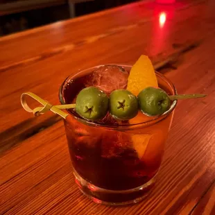 a cocktail with olives and a garnish