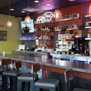 a bar with stools and televisions