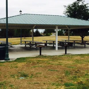 Large covered area with 5 long picnic tables and two double sized charcoal grills