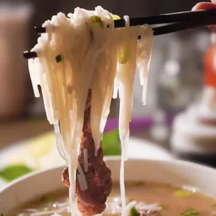 chopsticks lifting noodles from a bowl