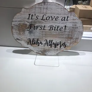a wooden sign saying it's love at first bite
