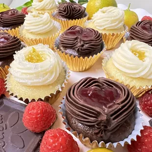 a plate of cupcakes with raspberries and chocolate