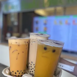 a hand holding two cups of bubble tea