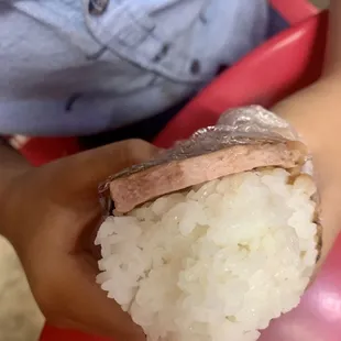 a person holding a piece of sushi