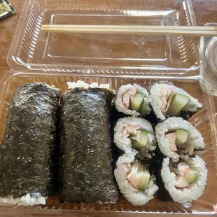 a plastic container with sushi and chopsticks