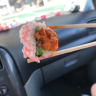 a person holding chopsticks over a sushi