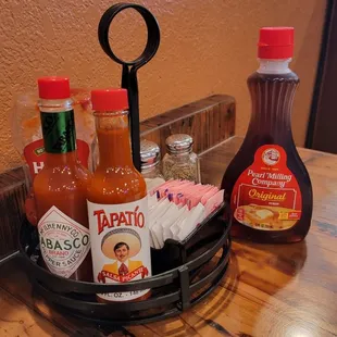 Table condiments ketchup, tabasco, tapatio, sugar, syrup, and salt &amp; pepper in the back