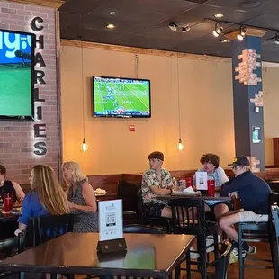 people sitting at tables and watching tvs