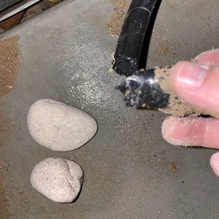a hand holding a piece of cement and a rock