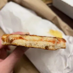 a hand holding a half eaten pizza