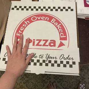 a hand reaching for a pizza