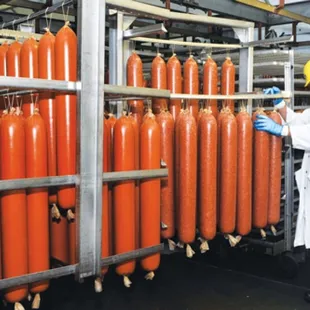 a man in a white lab coat and safety glasses inspecting a row of orange gas cylinders