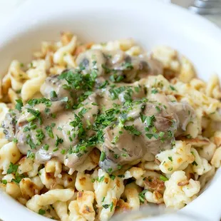 a bowl of pasta with meat and mushrooms