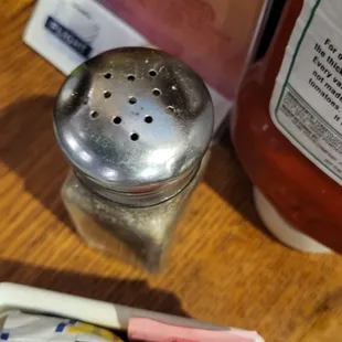 a salt shaker and packets of ketchup