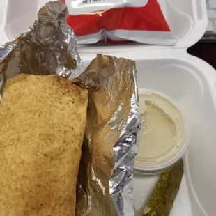 a sandwich and a pickle in a styrofoam container