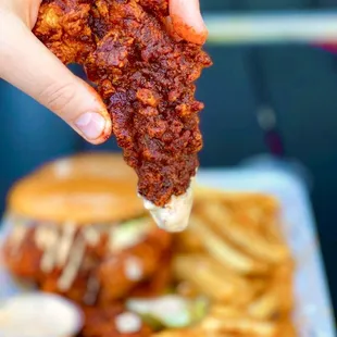 a hand holding a piece of fried chicken