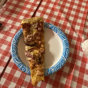 A slice of the King Kong pizza in a regular paper plate.