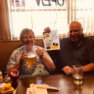 a man and a woman sitting at a table holding up a menu