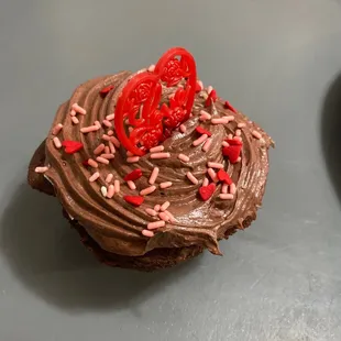 a chocolate cupcake with chocolate frosting and sprinkles