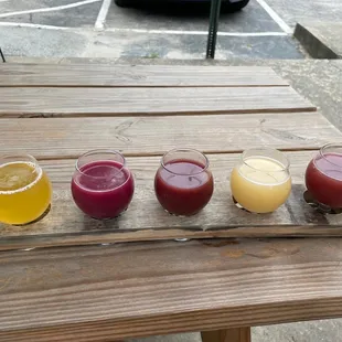 four glasses of juice on a wooden table