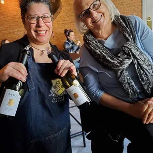 two women holding bottles of wine