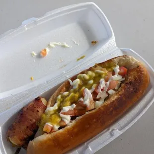 a hot dog in a styrofoam container