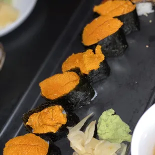 a variety of sushi on a black plate