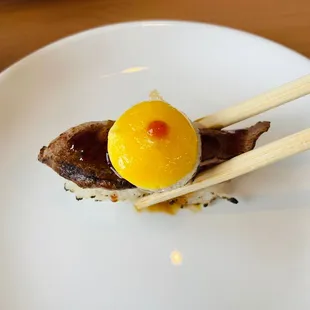 a piece of sushi on a plate with chopsticks