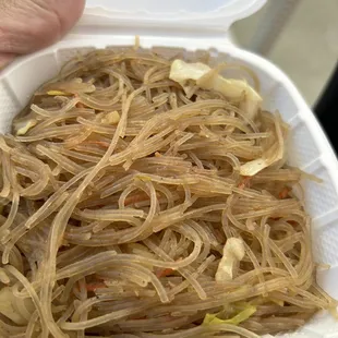 a hand holding a container of noodles