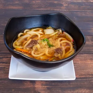 a bowl of noodles with meat and vegetables