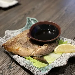 a plate of fish and a bowl of sauce