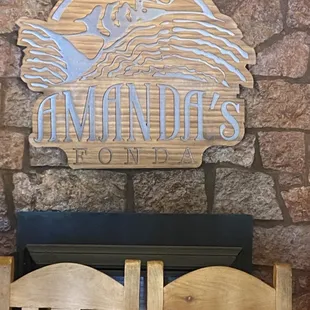 two wooden chairs in front of a stone wall