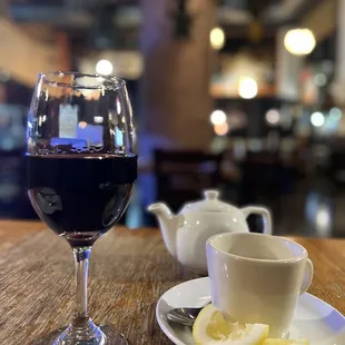 a glass of red wine and a plate of lemon slices